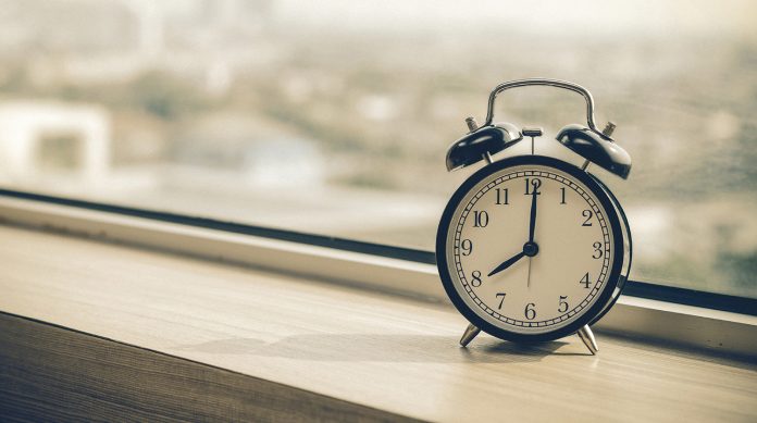 Vintage alarm clock at windows at early morning