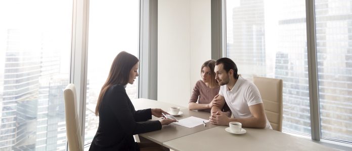 Young couple and real estate agent manager discussing contract agreement