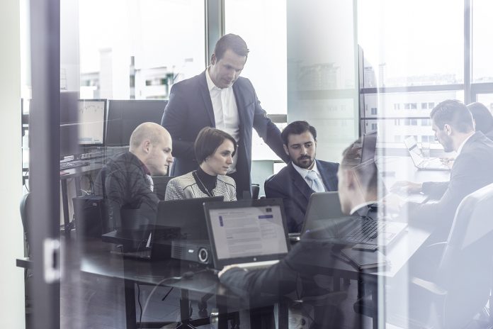 Business team working in corporate office seen trougt glass door.