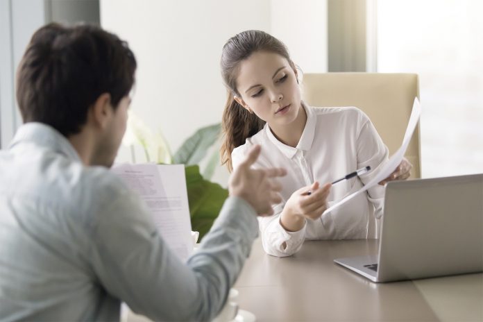 Conversation between businesswoman and businessman about documents at office table