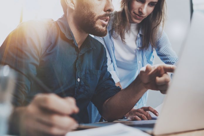 Group of coworkers sitting at the wooden table and working together on new startup project in modern loft office.Horizontal.Blurred background.Cropped.